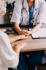 Obraz premium Doctor giving hope. Close up shot of young female physician leaning forward to smiling elderly lady patient holding her hand in palms. Woman caretaker in white coat supporting encouraging old person