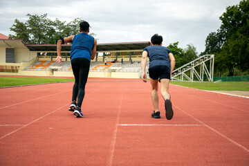 Obraz premium Two Asia male teenagers starting running in track for practice in Stadium