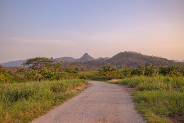 Country road down from the hill, mountain far away ahead, Thailand.