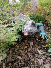 artificial garden figures of Iguanas on a flower bed with spicy herbs. Floral Wallpaper	