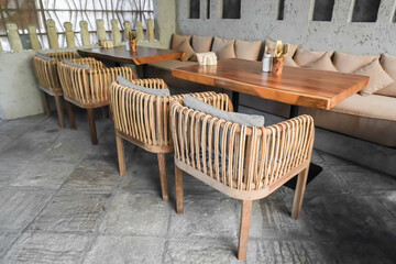 Indoor Cafe tables and chairs set made of wood and rattan. Natural interior design concept for tropical hotel, resort, villa, restaurant and cafe. Burlap sackcloth covered sofa and square pillows.