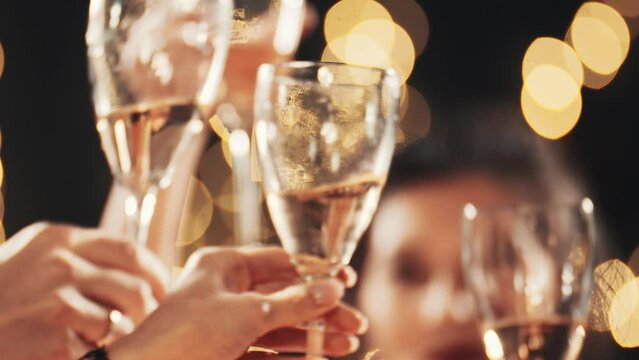 Stylish friends close up celebrating at glamorous merry Christmas new year birthday party making toast drinking champagne at formal social gathering enjoying evening celebration at Eve winter night.