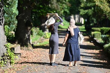 A young and an elder russian Orthodox women wearing a headscarf on their way to their family tombs.