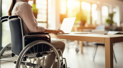copy space, stockphoto, Woman in a wheelchair working on a laptop in an office, handicap and disability. Disabled woman working with a laptop in an office environment. - obrazy, fototapety, plakaty