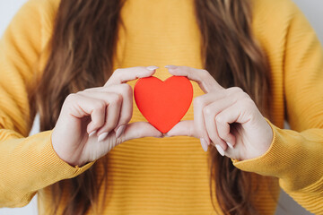 Love background. Red heart shape. Woman holding wooden heart. Young girl with heart in her fingers. Valentines day background. Showing emotion without words. Feelings background.