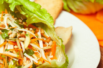 Vegan cuisine, healthy food concept. Fresh delicious vegetable salad - mix of celeriac, carrot, apple, iceberg lettuce and pine nut. Close up. Indoor shot