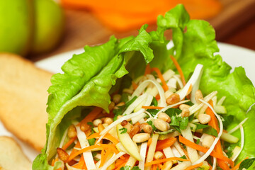 Vegan cuisine, healthy food concept. Fresh delicious vegetable salad - mix of celeriac, carrot, apple, iceberg lettuce and pine nut. Close up. Indoor shot