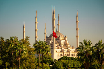 Turkish mosque in Adana city and Turkish flag. Symbol of Islamic culture and faith. Beautiful sacral building in Turkey.