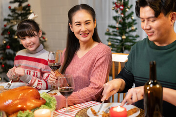 Happy Asian family smiling mother with father and daughter having dinner celebrating Christmas at home	