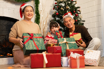 Obraz na płótnie Canvas Happy portrait Asian family Grand father, grandmother and grand daughter holding gift box with celebrating Christmas at home