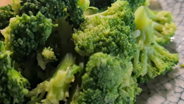 Broccoli with white sauce in a bowl and lemon in a plate. Vegetarian food