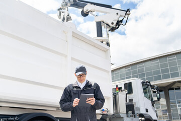 Manager with a digital tablet next to garbage truck