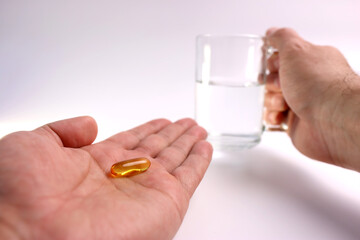A man holds a polyunsaturated fatty acid complex capsule in his hand. Prevention and treatment of ischemic heart disease, atherosclerosis of cerebral vessels.