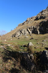 Fototapeta na wymiar A grassy hill with rocks and a hill with a blue sky