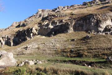 Fototapeta na wymiar A rocky mountain with grass and a blue sky
