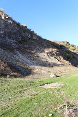 A grassy hill with a rocky cliff