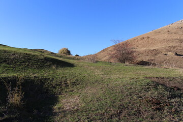 A grassy hill with a hill in the background