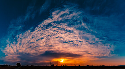 Sunset with a dramatic sky and overland high voltage lines near Tabertshausen, Deggendorf, Bavaria,...