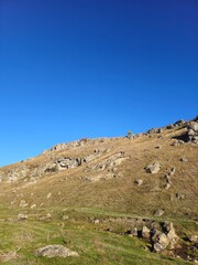 Fototapeta na wymiar A grassy hill with rocks and a blue sky