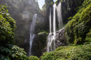 The Sekumpul Waterfall, a large waterfall in the middle of the jungle that falls into a deep green...