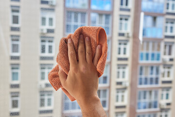 Male hand and yellow rag. A man's hand washes the window with a rag.