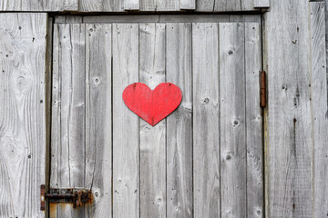Rustic wooden door on with rusty hardware, red wood heart symbolizing an outhouse
 - Powered by Adobe