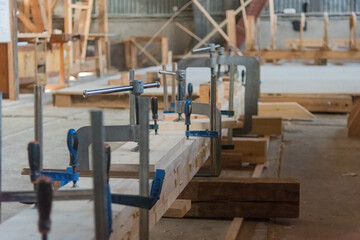metal clamps holding the glued board in the carpentry shop. natural light