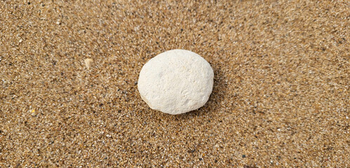 Fototapeta na wymiar White round stone on the river sand on the beach