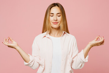 Young spiritual woman she wear shirt white t-shirt casual clothes hold spreading hands in yoga om aum gesture relax meditate try to calm down isolated on plain pastel pink background studio portrait.