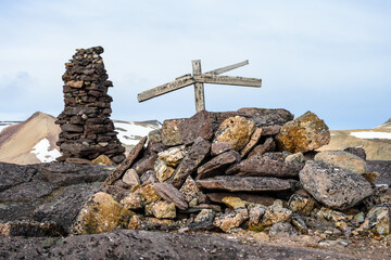 Rock cairn memorial marker and grave with wooded cross for whaler buried at Alicehamna, historical artifact, arctic expedition tourism around Svalbard
 - obrazy, fototapety, plakaty