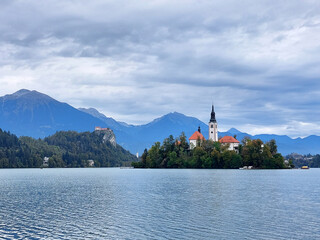 white church on island on lake Bled. Dark blue mountains. Slovenia.