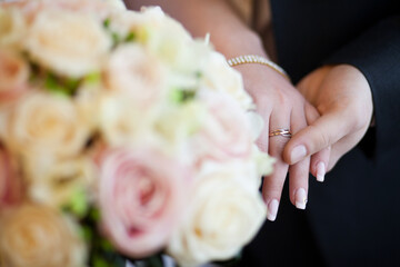 Bride and Groom's Hands with Wedding Ring Beside a Bouquet of Pale Roses