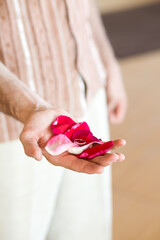 Man holding vibrant rose petals with a silver ring.