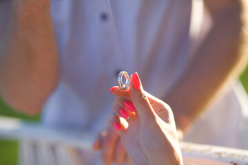 Close-up of woman's hand holding a silver pendant ring against a blurred background.