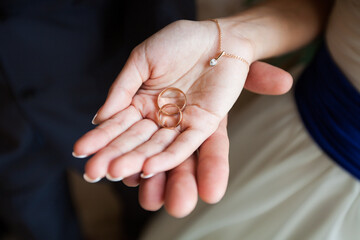 Bride's Hand Holding Wedding Rings with Delicate Bracele