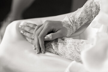 Bride's Hands with Lace Sleeves on Satin Wedding Dress in Monochrome