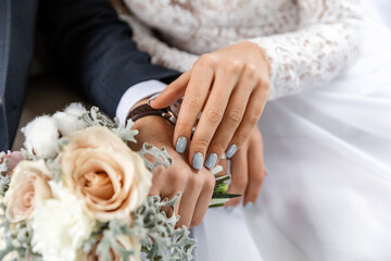 Close-up of a Bride's Hand with Light Blue Nail Polish, Holding a Bouquet with Pale Roses