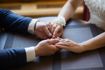 Obraz na płótnie Canvas Bride and Groom's Hands Together on a Table