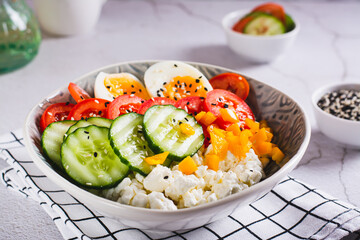 Cottage cheese bowl with tomatoes, cucumber, pepper and egg on the table