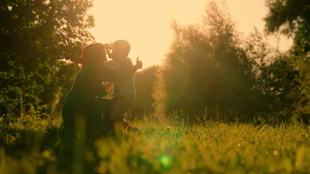 Carefree childhood, joyful embrace of child of mother. Child, son runs to mom, hugs her in park. Happy family, Kid. Child has fun in summer on street with mother. Family Mom, kid boy outdoors sun day