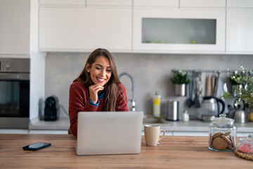 Portrait of cheerful businesswoman with hand on chin while having video call on laptop computer in...