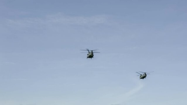 close-up of a pair of RAF Chinook tandem-rotor CH-47 helicopters flying directly overhead