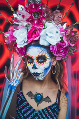 Mexican woman dressed and characterized as a catrina for the Day of the Dead festivity, behind her an orange background like the cempasuchil flower.