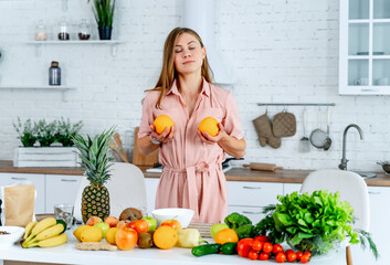 Kitchen Magic: A Woman's Citrus Delight. A woman standing in a kitchen holding two oranges