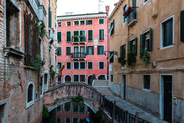Fototapeta na wymiar Scenic canal with bridge and ancient buildings with potted plants in Venice, Italy