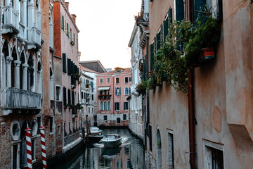 Fototapeta na wymiar Scenic narrow canal with ancient buildings with potted plants in Venice, Italy
