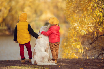 Girl and boy with white big dog in autumn park 