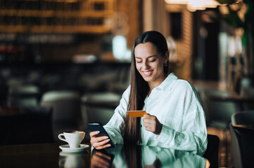Portrait of a cheerful young trendy woman sitting in a cafe and having her coffee