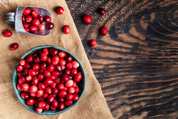 Fresh cranberries in wooden bowl on dark wooden table. View from above.Space for text.