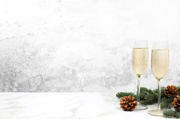Two glasses of champagne on an elegant festive background with fir branches and decorations, Christmas Eve concept. Christmas and New Year mockup for design and product display,